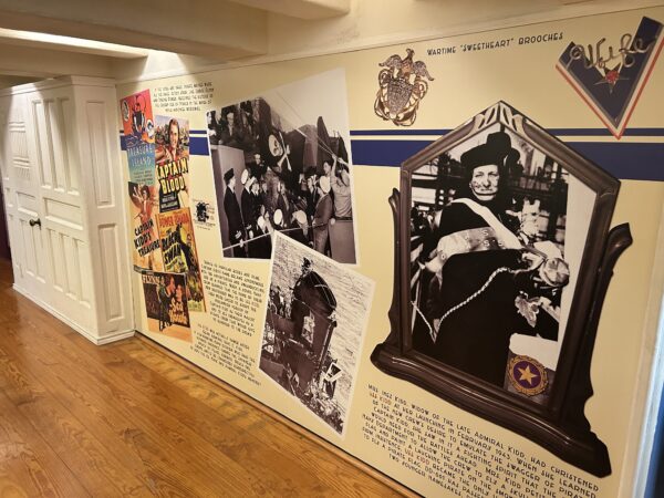A wall display with several photos depicting the crew of USS KIDD flying the first Jolly Roger flag over the ship, the wife of Rear Admiral Isacc Kidd, and the Captain Kidd mascot adopted by the ship and painted on the smokestack.